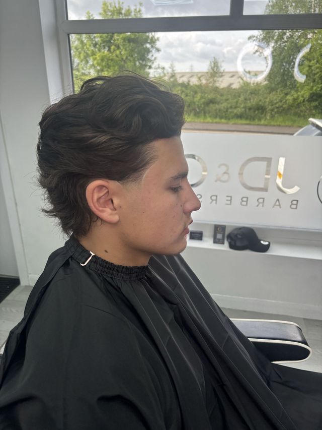 Curly top with tapered sides styled at JD&Co Barbershop